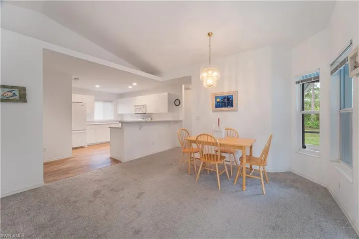 Carpeted dining space with a chandelier and vaulted ceiling