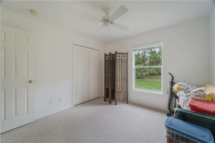 Bedroom with ceiling fan, a closet, and light carpet