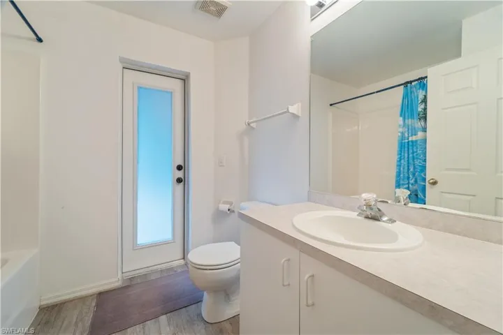 Full bathroom with shower / tub combo, oversized vanity, toilet, and wood-type flooring