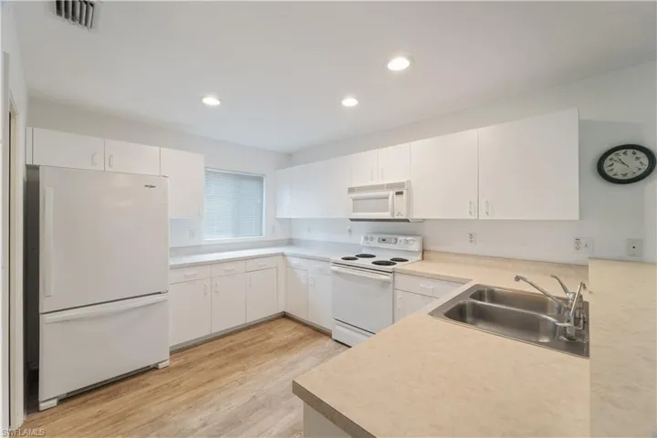 Kitchen featuring white cabinets, sink, white appliances, and light hardwood / wood-style floors