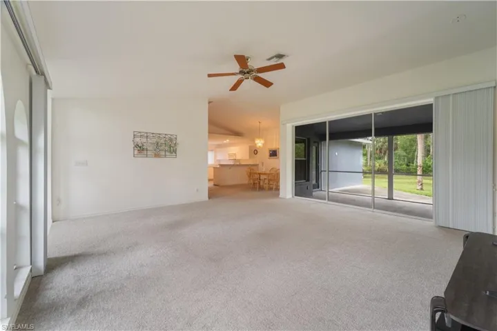 Unfurnished living room with carpet, ceiling fan, and vaulted ceiling