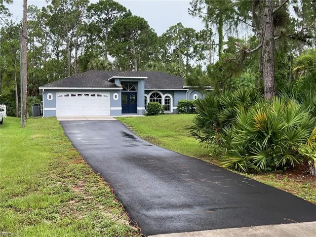 Ranch-style home featuring a garage and a front lawn