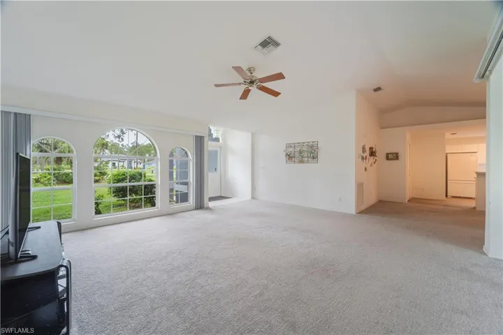 Living room with lofted ceiling, carpet floors, and ceiling fan