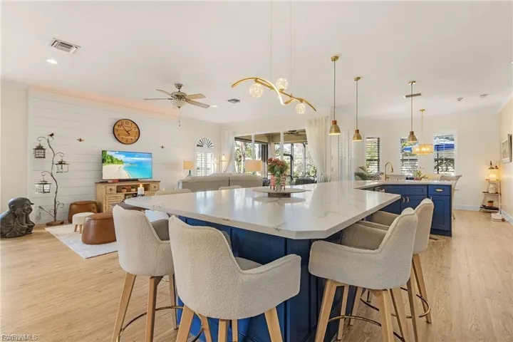 Kitchen with blue cabinetry, open floor plan, light wood-style floors, a kitchen breakfast bar, and ornamental molding