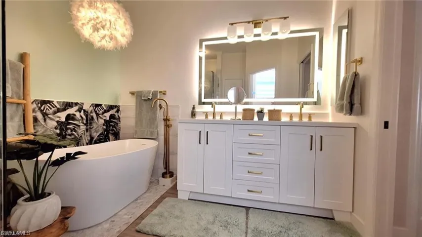 Bathroom with double vanity, a freestanding bath, and tile walls