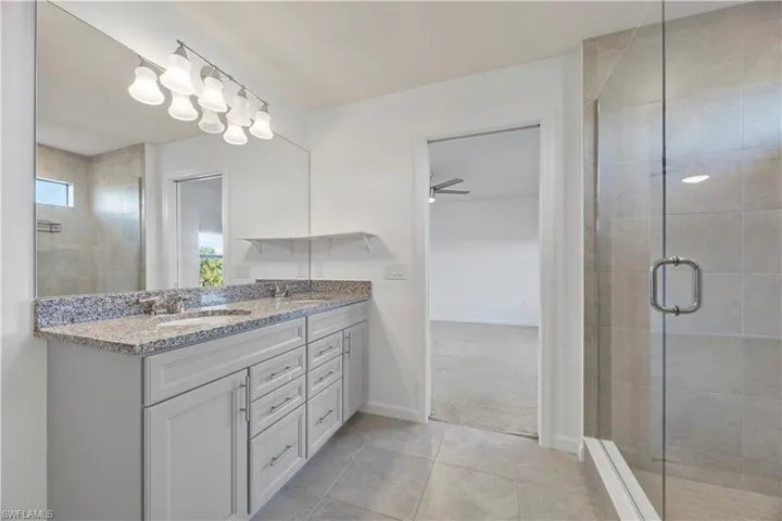Full bath featuring double vanity, a stall shower, and light tile patterned floors