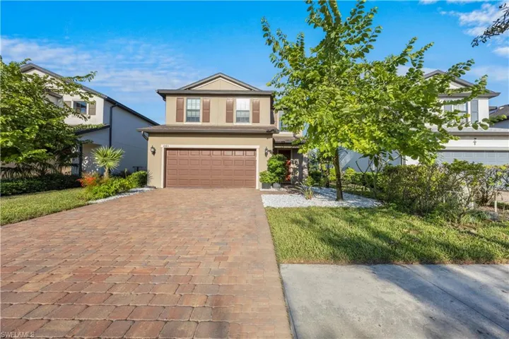 View of front of home featuring stucco siding, decorative driveway, an attached garage, and a front lawn