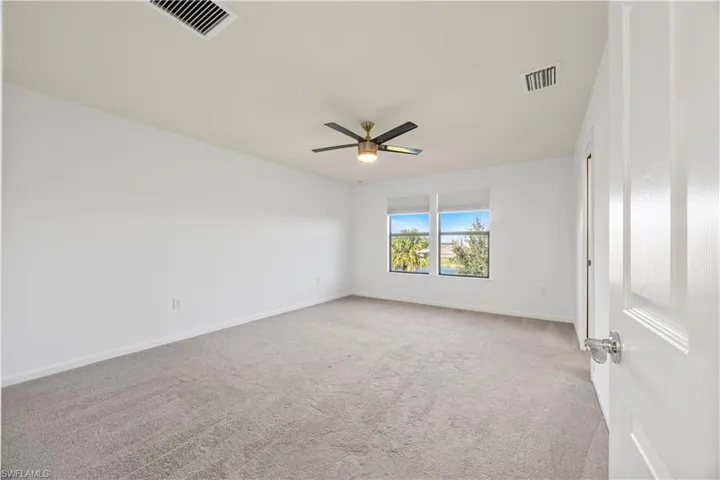 Carpeted spare room featuring ceiling fan and baseboards