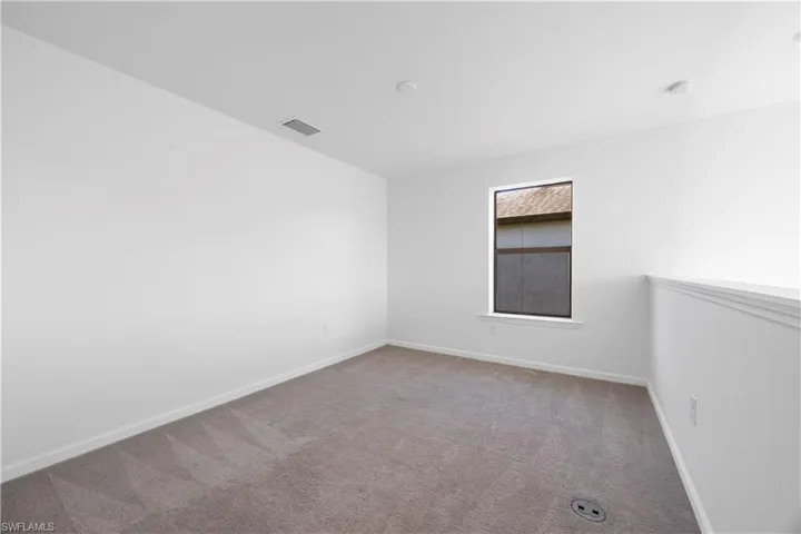 Carpeted spare room featuring baseboards