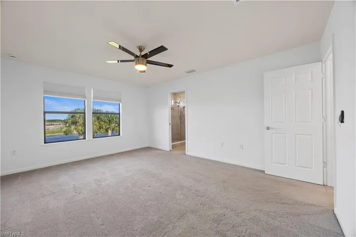 Unfurnished bedroom with light colored carpet, a ceiling fan, and ensuite bath