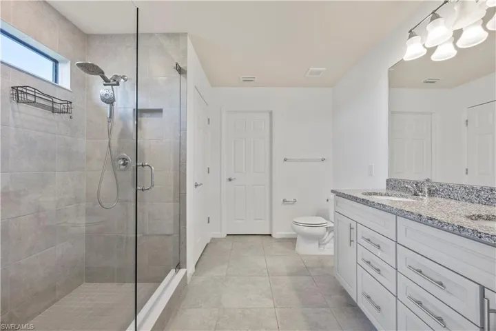 Bathroom with double vanity, a stall shower, and light tile patterned flooring