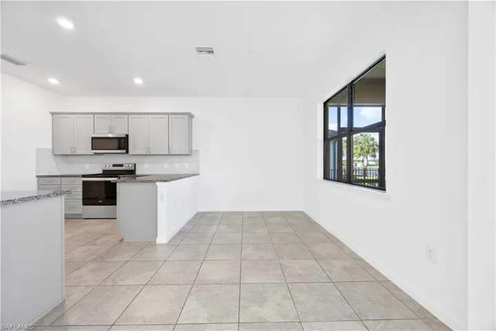 Kitchen featuring tasteful backsplash, appliances with stainless steel finishes, light tile patterned flooring, dark stone counters, and recessed lighting