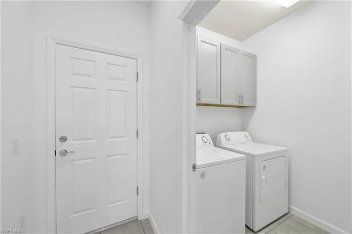 Laundry room featuring light tile patterned floors, cabinet space, and washing machine and clothes dryer