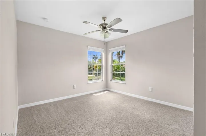 Carpeted spare room with baseboards and ceiling fan