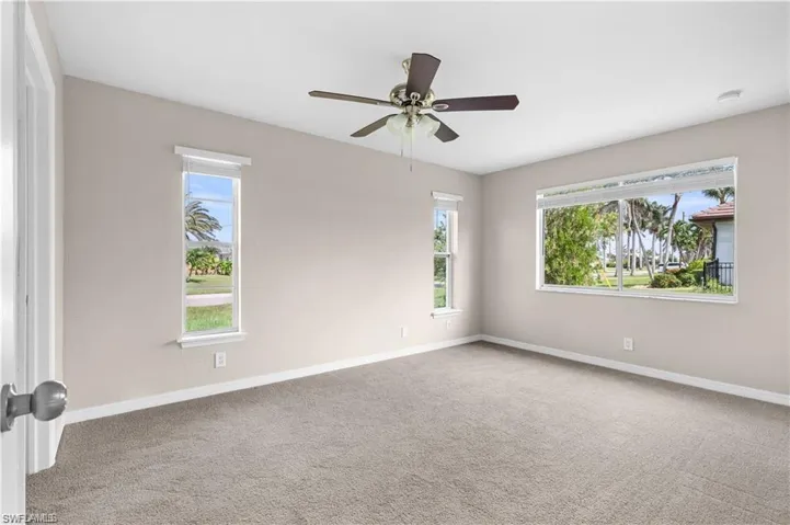 Unfurnished room featuring light colored carpet, healthy amount of natural light, and ceiling fan