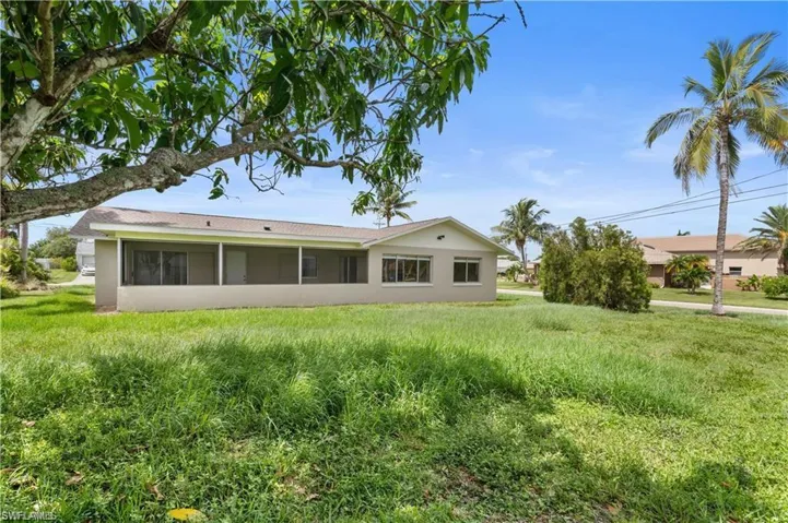 Rear view of house with stucco siding, a sunroom, and a lawn