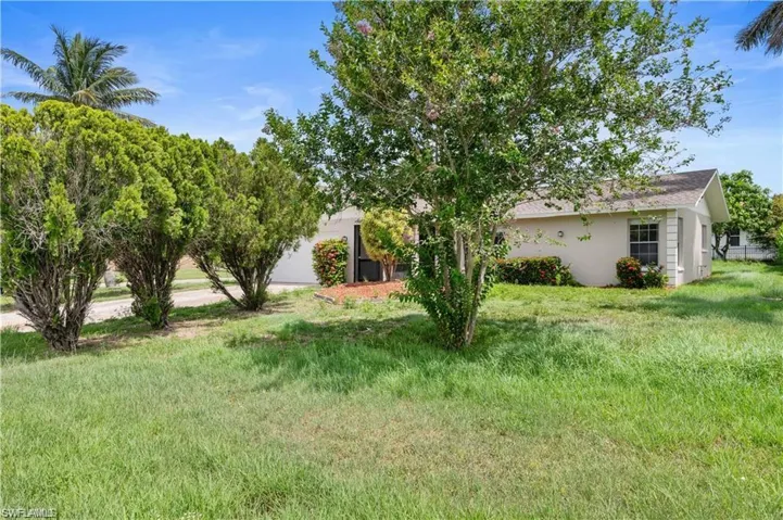 View of green lawn with a garage and driveway