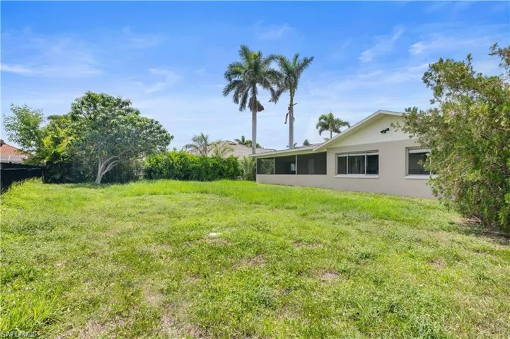 View of grassy yard featuring a sunroom