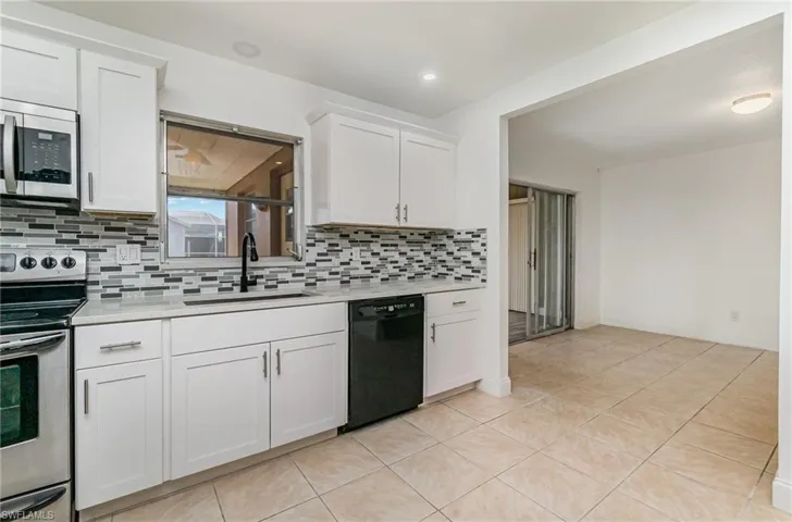 Kitchen featuring appliances with stainless steel finishes, light countertops, tasteful backsplash, white cabinets, and light tile patterned floors