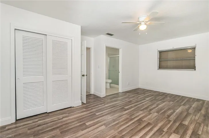 Unfurnished bedroom featuring a closet, wood finished floors, ensuite bathroom, and ceiling fan