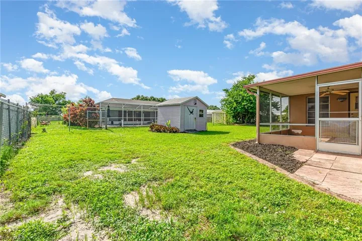 Fenced backyard featuring a sunroom, ceiling fan, and a storage unit