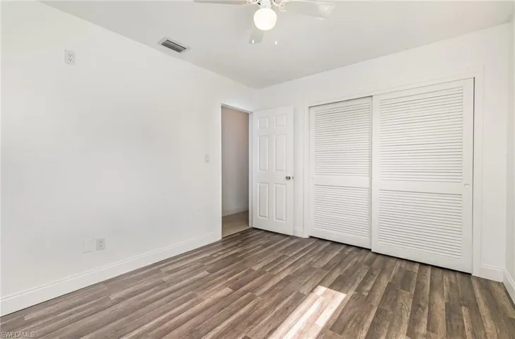 Unfurnished bedroom with wood finished floors, a closet, and a ceiling fan