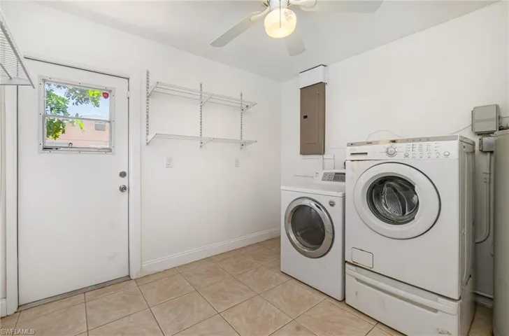 Laundry area with washing machine and clothes dryer, ceiling fan, electric panel, and light tile patterned flooring
