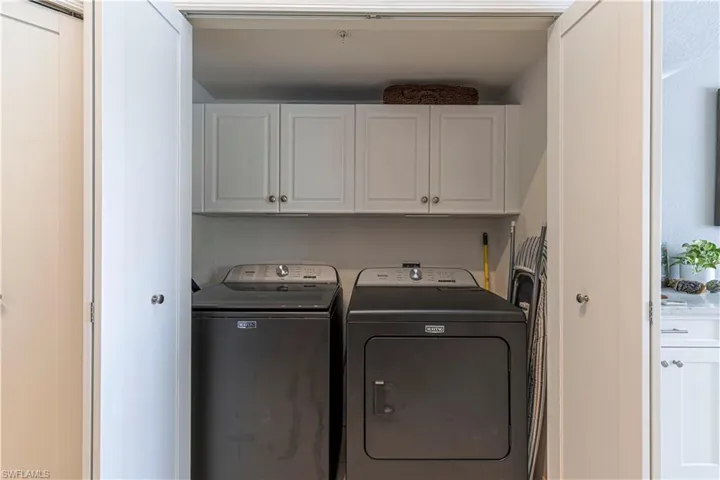 Dedicated laundry closet with white shaker-style cabinetry and a shelf