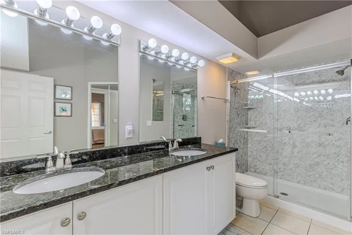 Dual vanity with granite countertops, white cabinetry, and undermount sinks