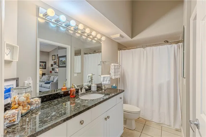 Bathroom featuring a vanity with a dark speckled countertop, an undermount sink, and polished chrome fixtures