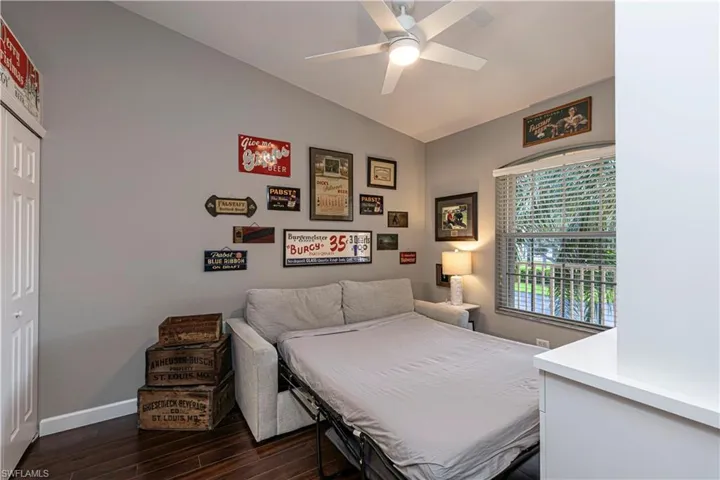 Room featuring wood-finish flooring, a ceiling fan, a window with blinds, and white bi-fold closet doors