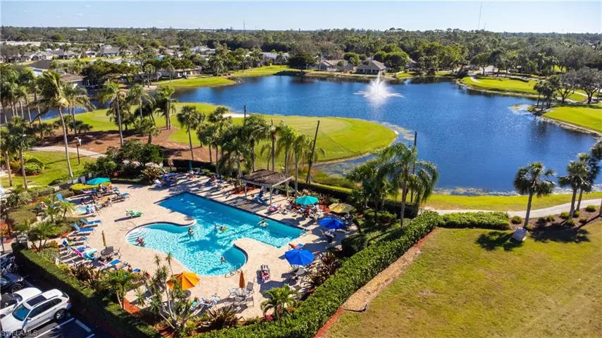 Community swimming pool with surrounding lounge areas, tropical landscaping, and a water feature