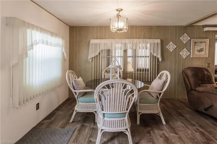Dining space with and luxury vinyl plank flooring, wood walls, and inviting lighting