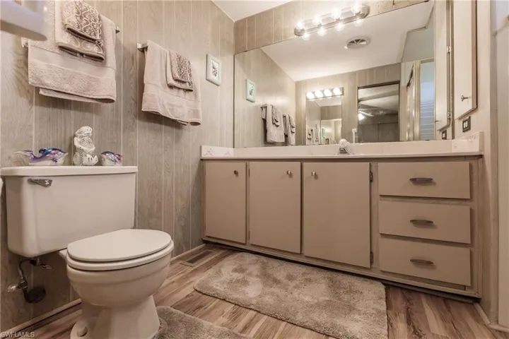 Bathroom featuring laminate flooring, vanity, and toilet