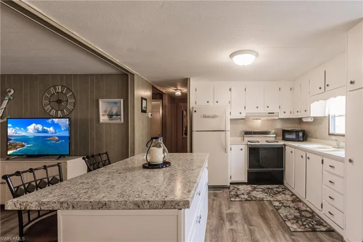 Kitchen with wood-type flooring, white appliances, white cabinetry, and and luxury vinyl plank flooring