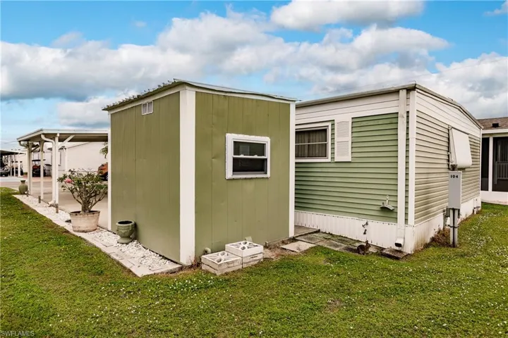 View of side of property with a storage shed and lawn