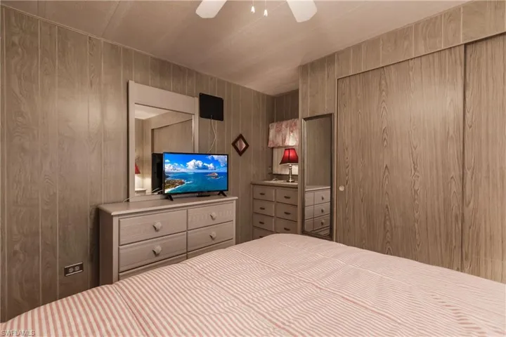 Peaceful bedroom with ceiling fan, wooden walls, and windows
