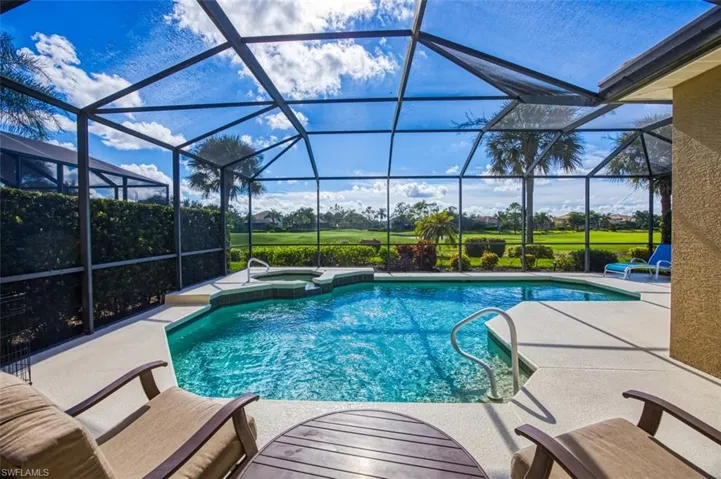 View of swimming pool featuring a patio, glass enclosure, and an in ground hot tub