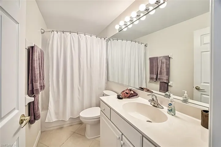 Full bathroom with vanity, toilet, shower / bathtub combination with curtain, and tile patterned floors