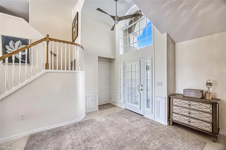 Tiled foyer with ceiling fan and a towering ceiling