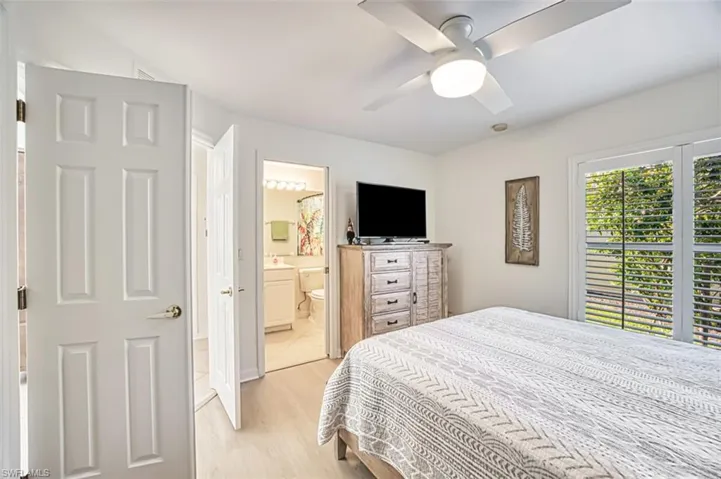 Bedroom with ceiling fan, light wood-type flooring, and ensuite bathroom