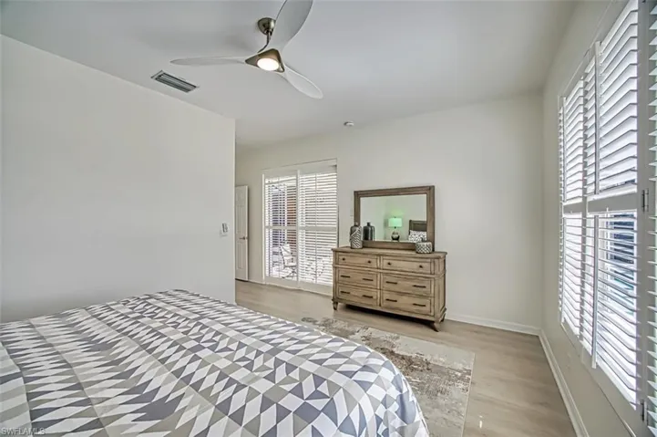Bedroom featuring light hardwood / wood-style flooring, ceiling fan, and multiple windows