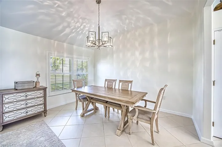 Dining space with light tile patterned flooring and a chandelier