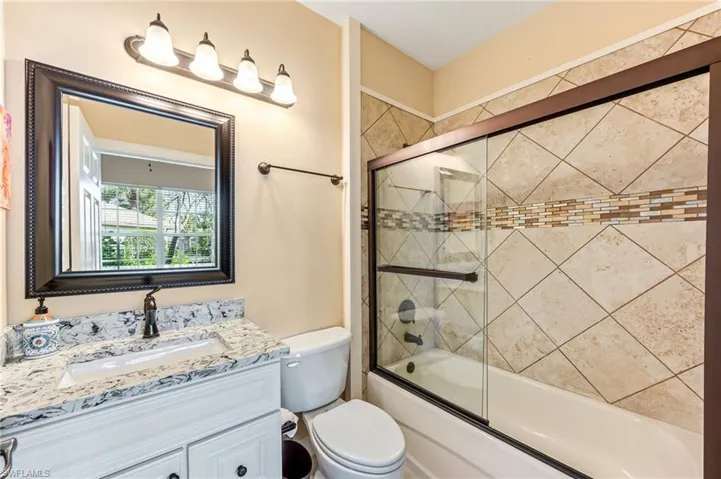 Full bathroom featuring toilet, vanity, and enclosed tub / shower combo