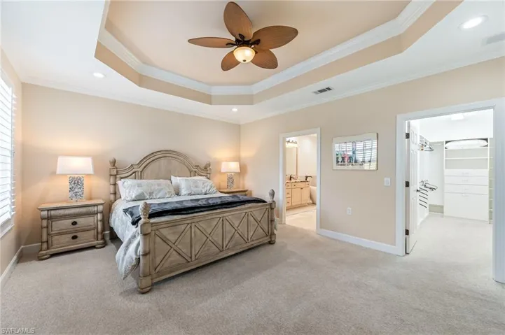 Bedroom with ornamental molding, a tray ceiling, and carpet