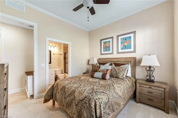 Bedroom with baseboards, ornamental molding, connected bathroom, and light carpet