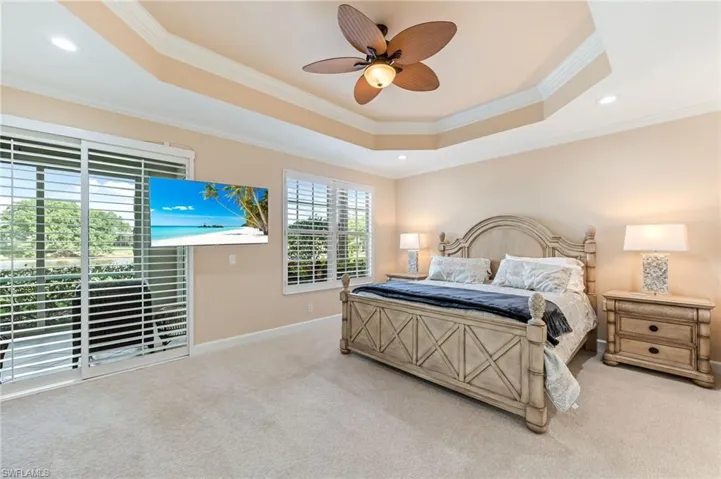 Carpeted bedroom with a tray ceiling, baseboards, ornamental molding, and recessed lighting