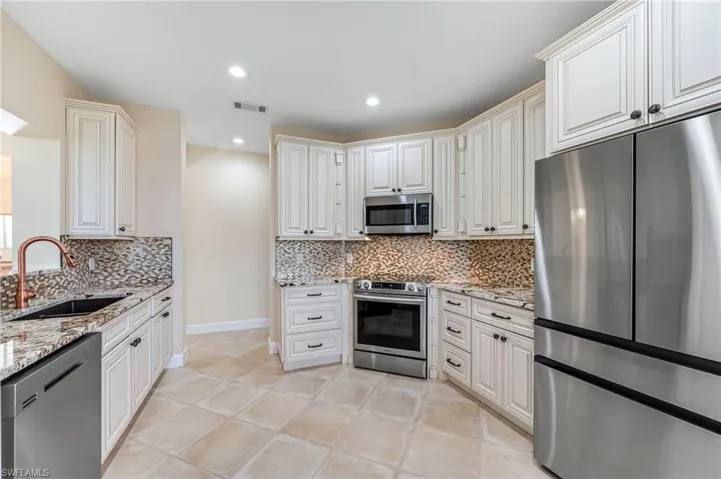 Kitchen with light stone countertops, a sink, and stainless steel appliances