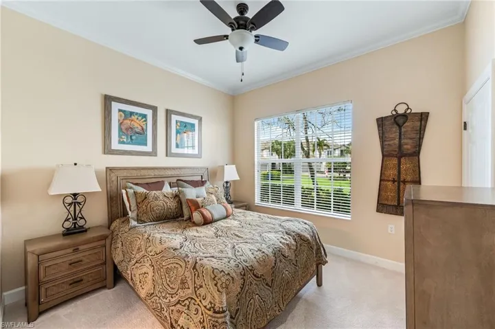 Bedroom with crown molding, baseboards, ceiling fan, and light carpet