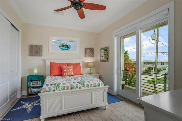 Bedroom with ornamental molding, porcelain plank tile  flooring, access to outside balcony, a double closet, window shade and ceiling fan